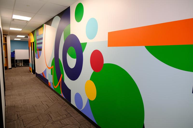 Wide corridor view of overlapping circles in green, violet and light blue, cut by a horizontal orange bar.