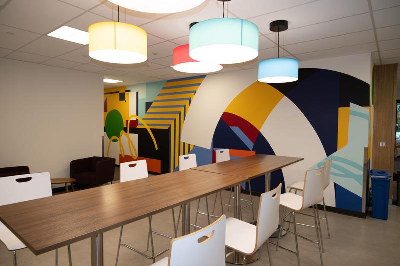 Co.Labs kitchen and meeting area with pendant lights, the mural's arc forms filling the wall behind the communal table.