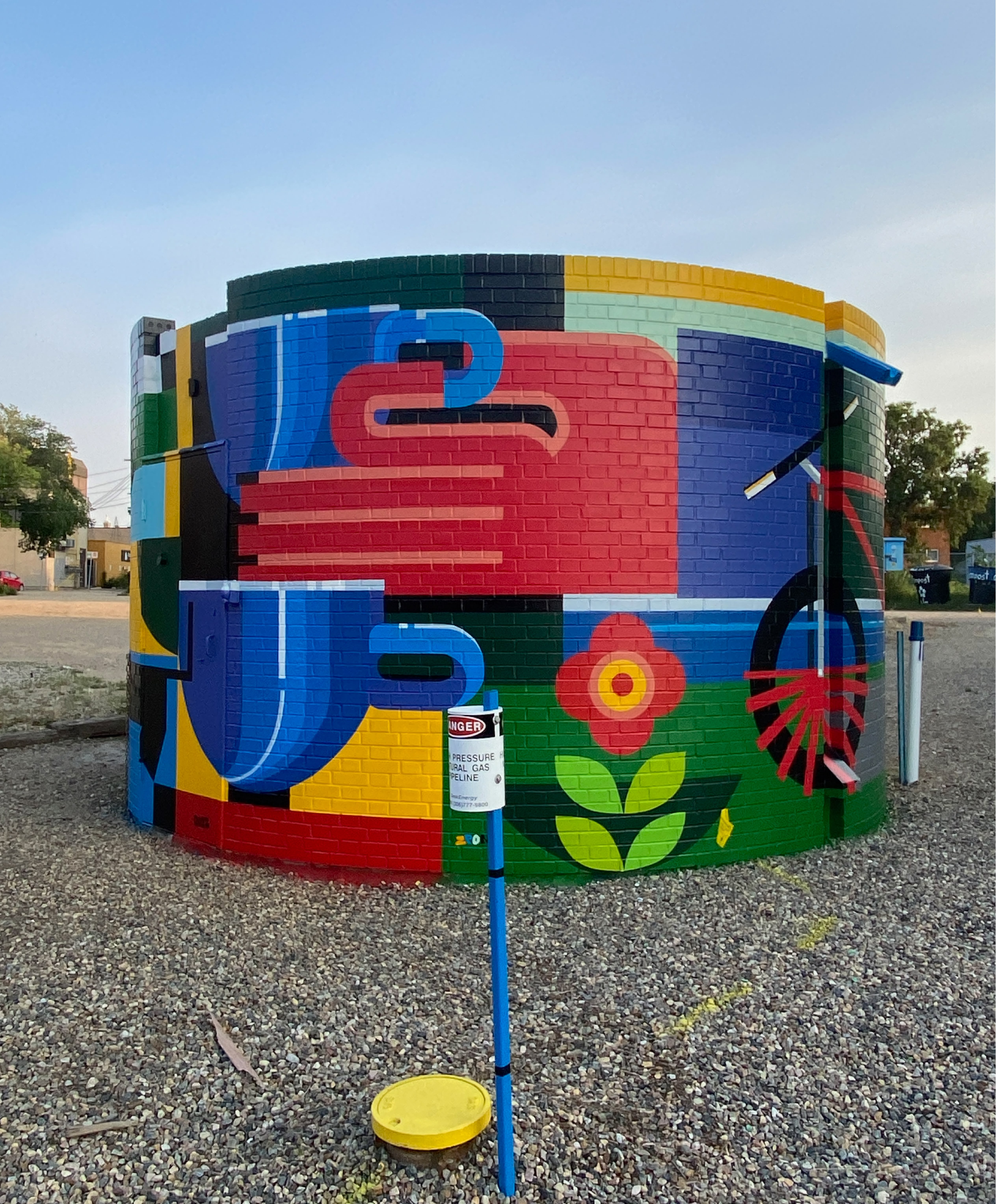 Geometric mural on Broadway in Saskatoon illustrating daily neighborhood life through bold color and abstract forms.